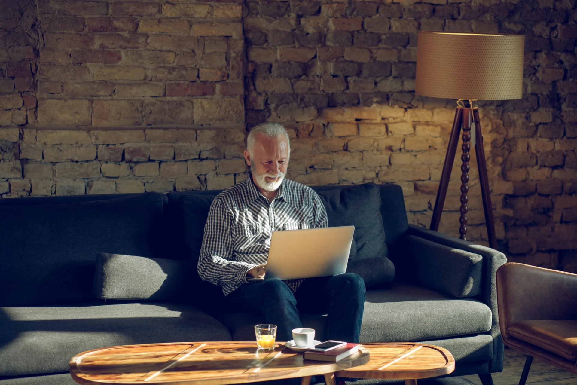 Elderly man using laptop on sofa
